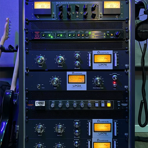 Rack of analog compressors with illuminated VU meters in the That Pro Mix studio